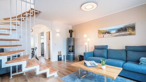 Ein modernes Wohnzimmer mit einer Holztreppe, einem blauen Sofa, einem Holztisch und einem Kamin.