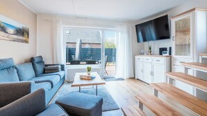 Ein modernes Wohnzimmer mit einer Couch, einem Couchtisch und einem Fernseher.