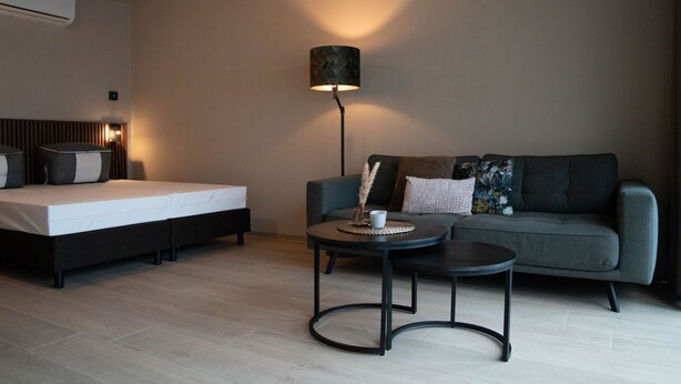 Een moderne kamer met een bed, een bank, een kleine tafel en een vloerlamp.