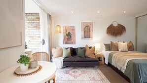 Un dormitorio acogedor con una cama, un sofá, una mesita con una planta y una lámpara de pared.