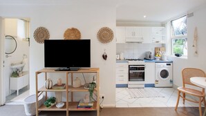 Una cocina moderna con armarios blancos, estufa a gas, lavadora y comedor con una silla y mesa.