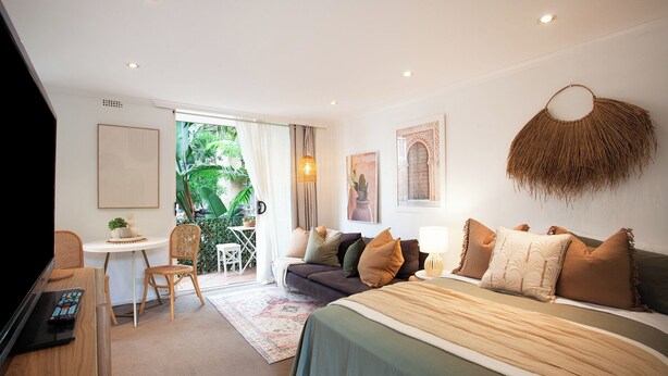 Un dormitorio con cama, escritorio, silla y vistas al exterior.