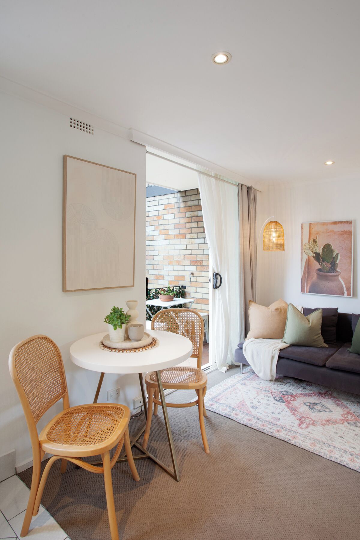 Un salon moderne comprenant un coin repas, un ensemble de canapés et donnant sur un mur en briques.