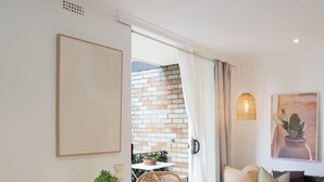 Una sala de estar moderna con comedor, un conjunto de sofá y vistas a un muro de ladrillo.