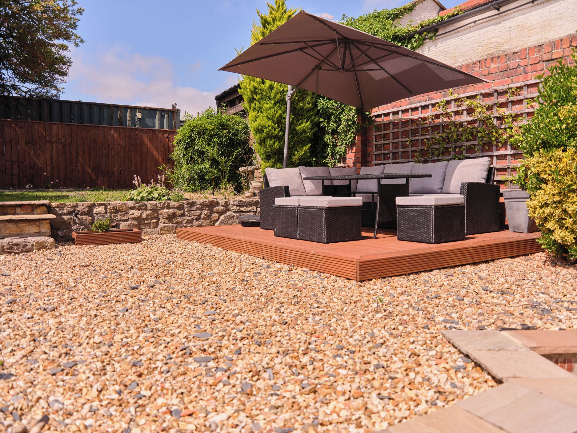 An outdoor patio with a seating area, a table, and a large umbrella.