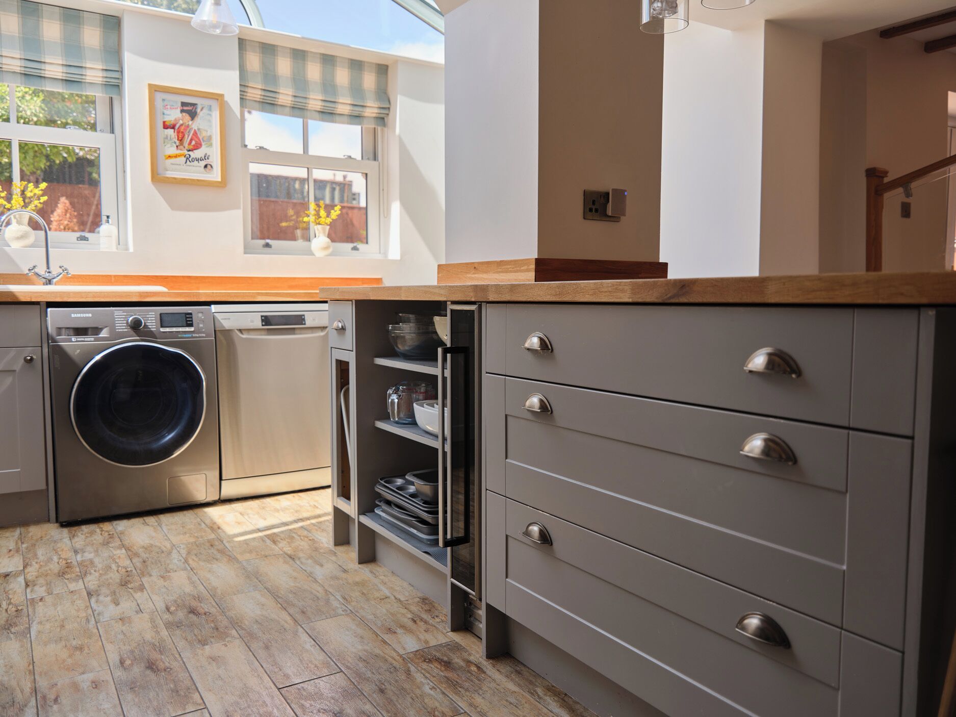 A compact kitchen with a washing machine, dishwasher, and grey cabinets.