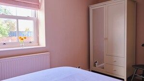 Una camera da letto con un letto, un armadio, un termosifone, una finestra con vista e una sedia.