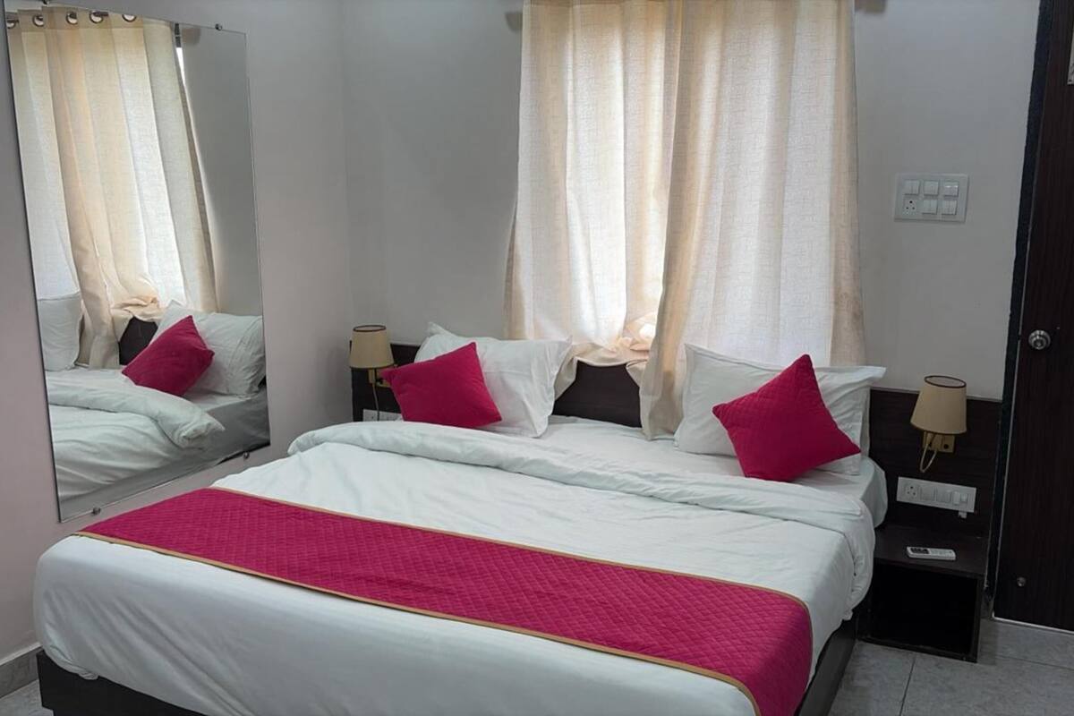 A hotel room with a large bed, two bedside tables, a mirror, and a door.