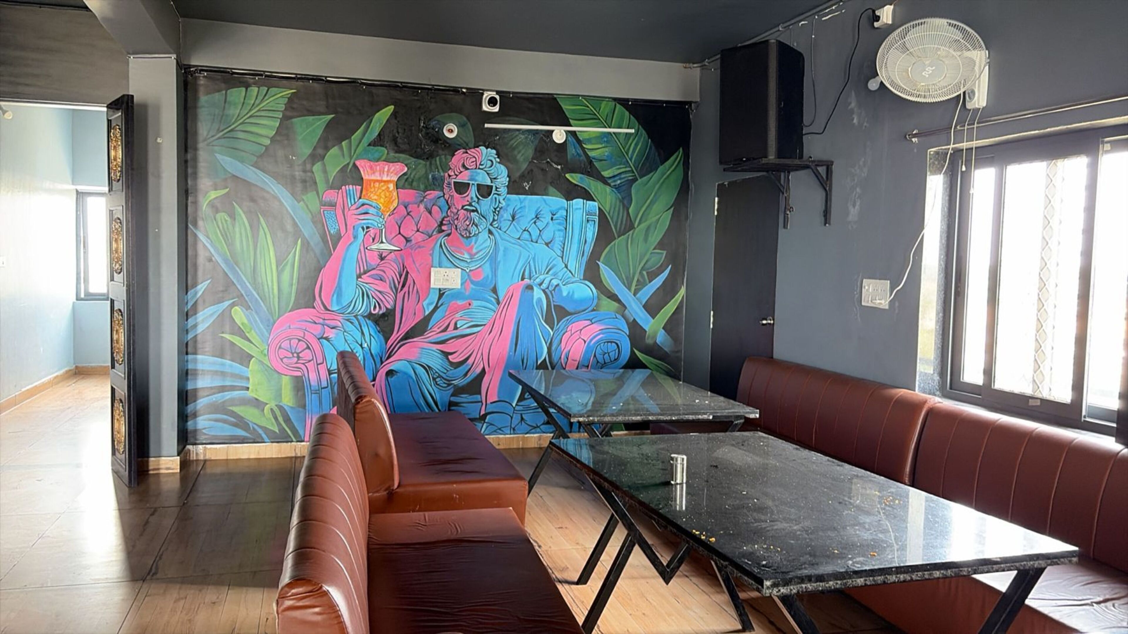 Decoração moderna com um mural, assentos de couro, mesa de vidro e um ventilador.