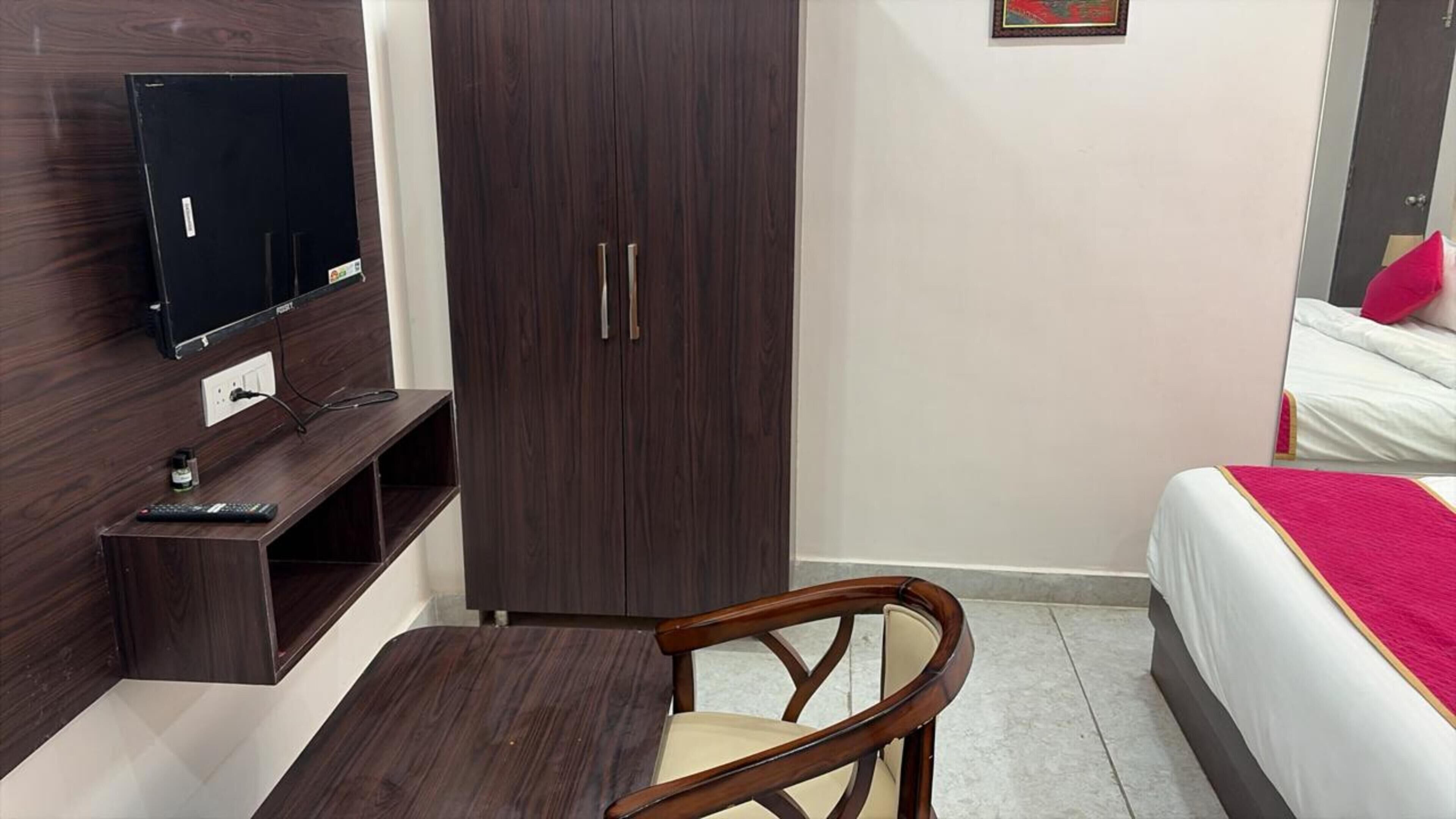 Une chambre à coucher comprenant un lit, un téléviseur fixé au mur, un bureau en bois et une armoire.