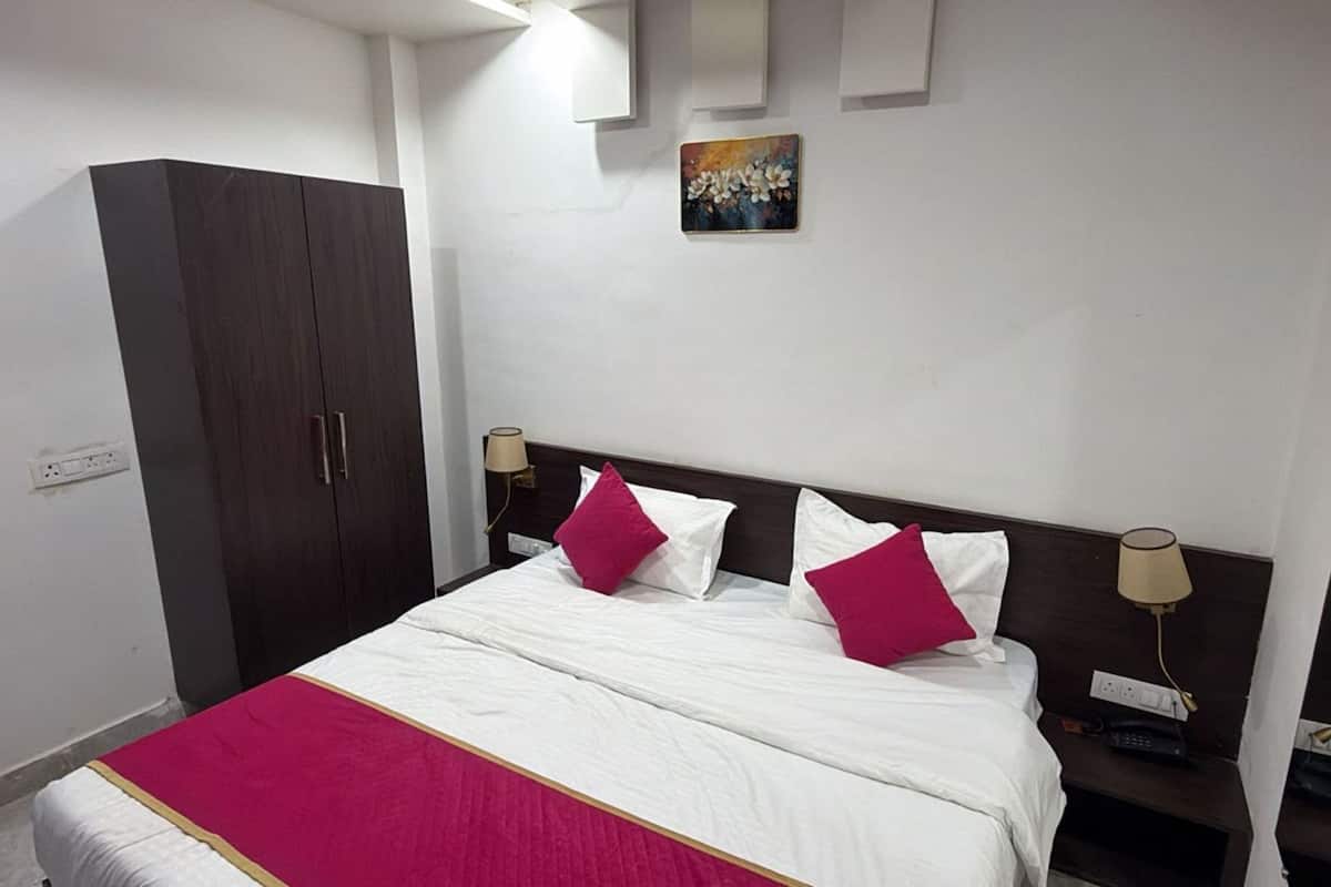 A hotel room with a bed, a wardrobe, a painting on the wall, and bedside lamps.