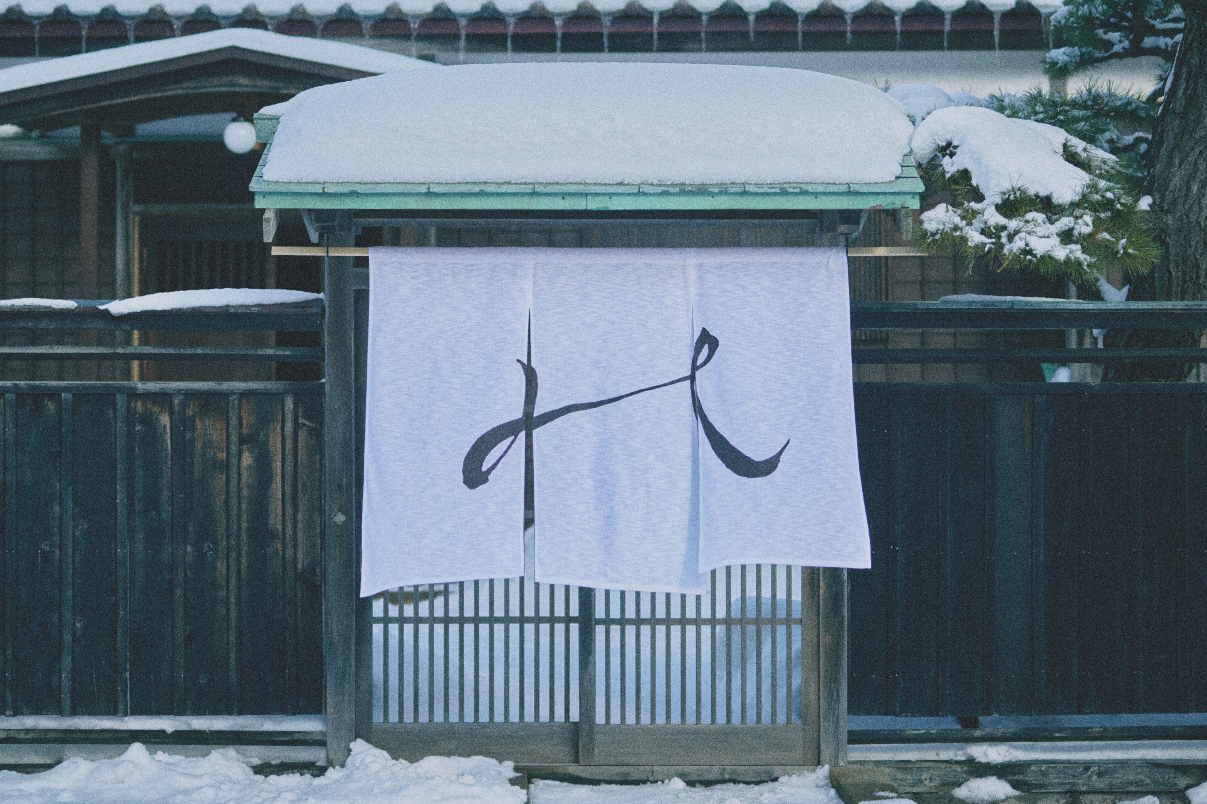 A wooden structure with a white cloth featuring a black design, surrounded by snow.