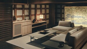 A traditional Japanese-style room with tatami flooring, a low table, a sofa, a cabinet, and a sliding door. - Old Soma Residence Kazeno Heritage (Hakodate)