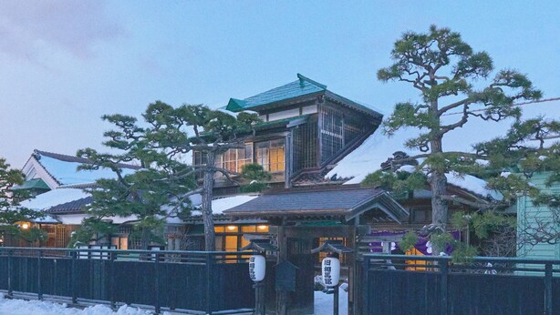 A traditional Japanese building with a sloped roof and wooden structure, surrounded by snow. - Old Soma Residence Kazeno Heritage (Hakodate)