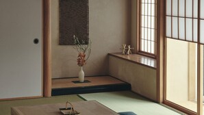 A traditional Japanese room with tatami flooring, a low table, a vase with flowers, and a shoji screen. - Old Soma Residence Kazeno Heritage (Hakodate)