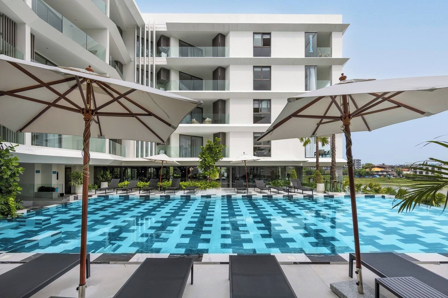 Ein modernes Hotel mit Pool auf dem Dach, Liegestühlen und Sonnenschirmen.