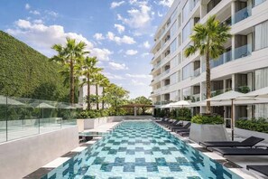 Una piscina sul tetto con lettini, una ringhiera in vetro e un edificio con balconi.
