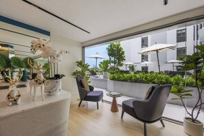 Un interno moderno con un'area salotto, una reception con oggetti decorativi e vista sulla terrazza esterna.