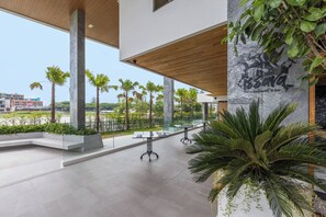 Un intérieur moderne avec une balustrade en verre, des palmiers et une vue sur l’extérieur.