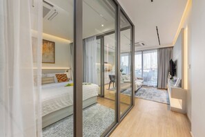 A modern hotel room with a large bed, a seating area, and a view of the city. - The Aqua Luxury Apart Hotel Waterfront (Choeng Thale)