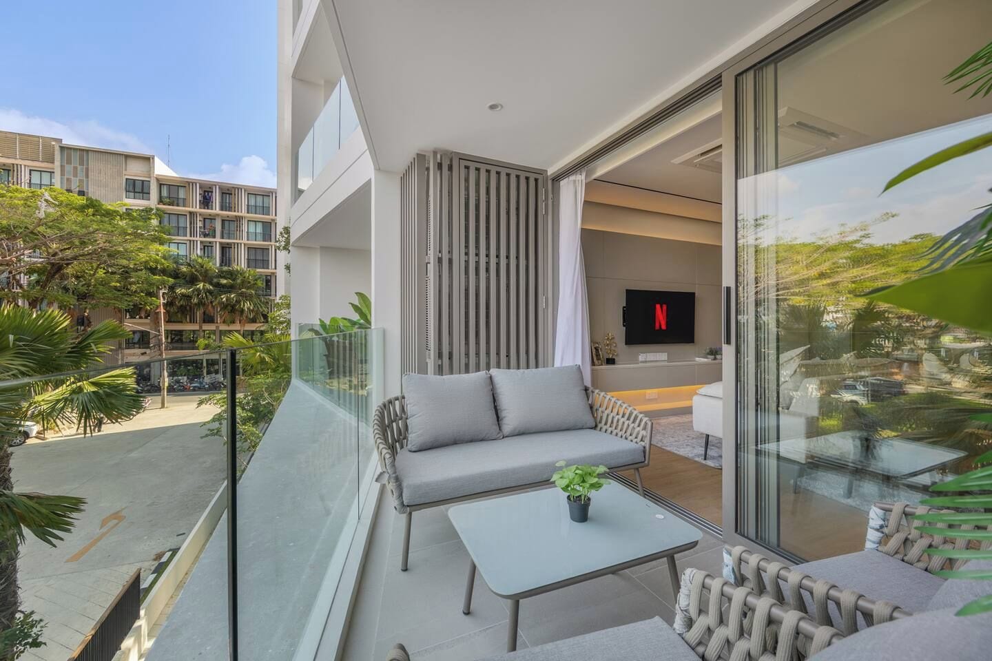 A balcony with a sofa, a table, and a potted plant.