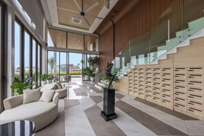 A modern lobby with a seating area, a staircase, and a wall of lockers. - The Aqua Luxury Apart Hotel Waterfront (Choeng Thale)