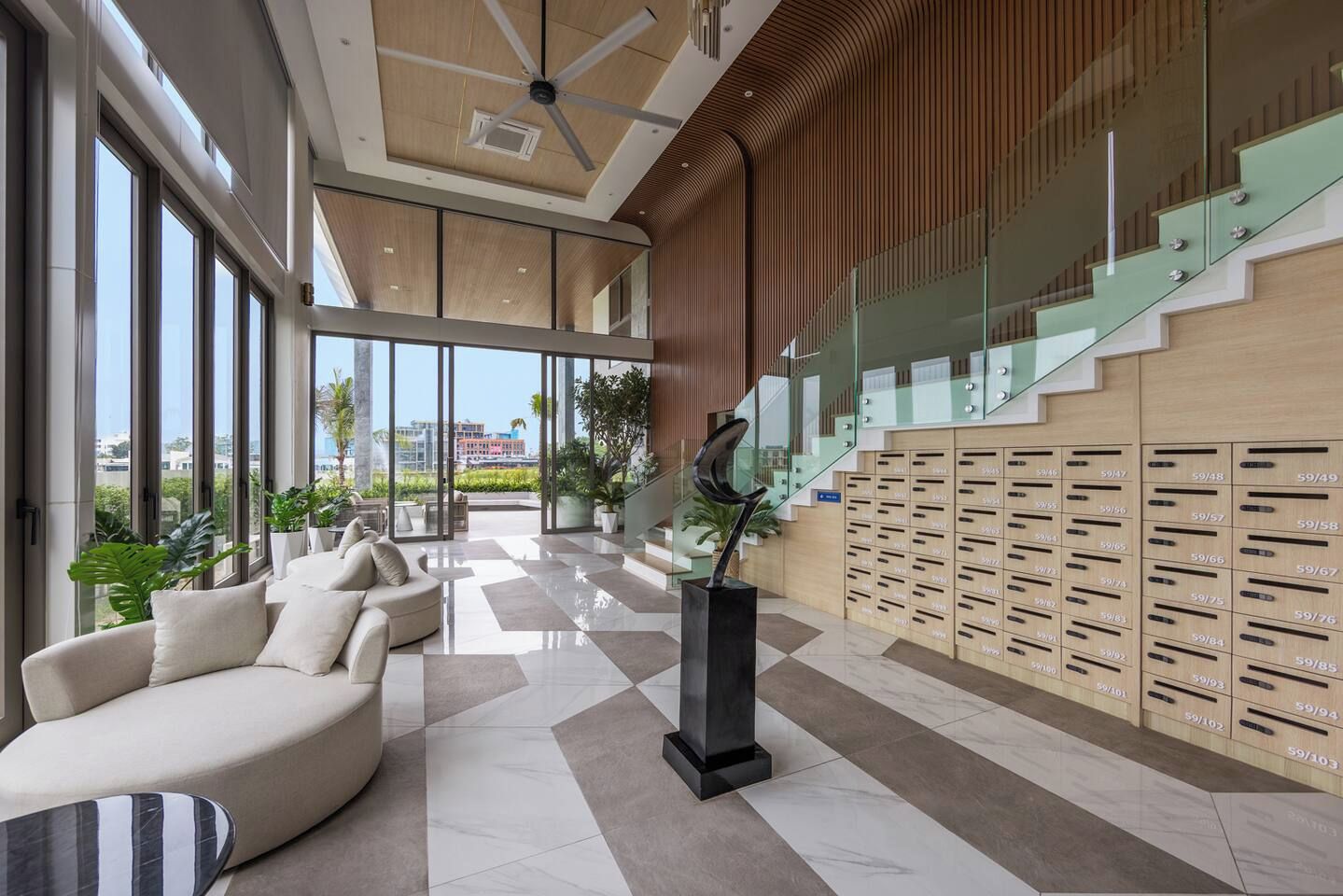 A modern lobby with a seating area, a staircase, and a wall of lockers.