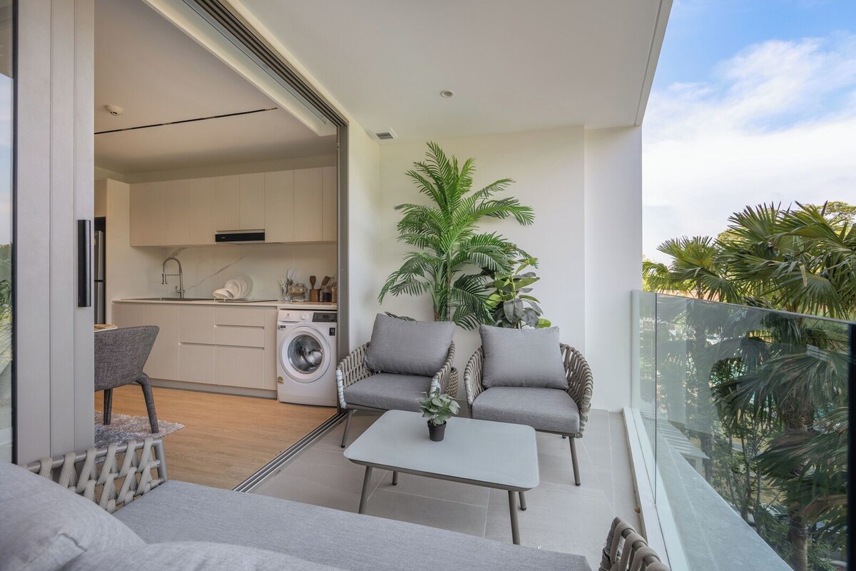 Ein Balkon mit einer Couch, einem Tisch und einer Waschmaschine im Hintergrund.