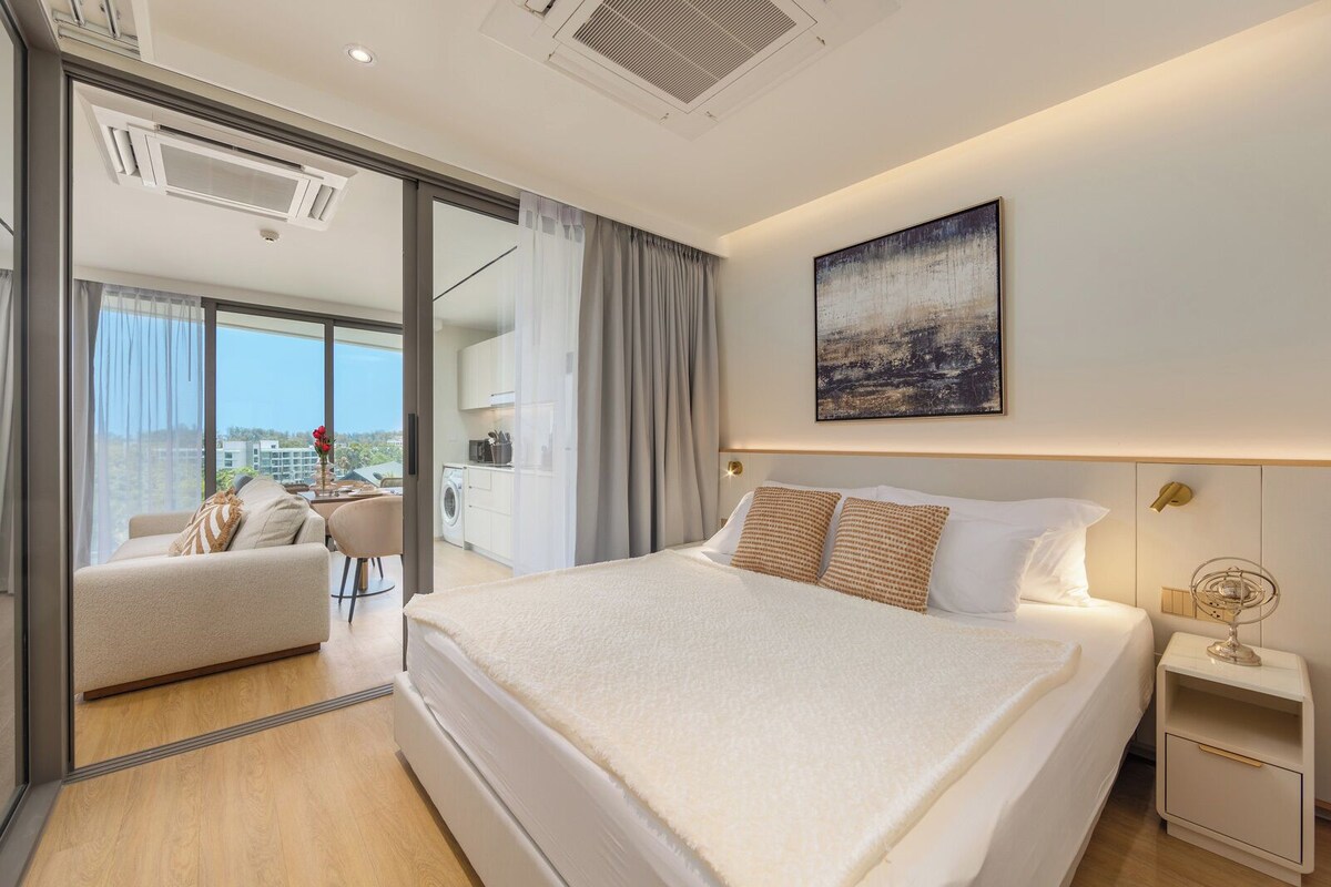 Ein modernes Hotelzimmer mit einem großen Bett, einem kleinen Nachttisch, Blick auf die Stadt und einem Balkon mit einem Stuhl.