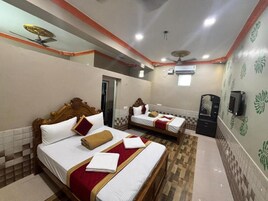 Una habitación de hotel con dos camas, ventilador de techo, aire acondicionado y televisor.
