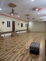 Una habitación amplia con suelo de madera estampado, una escalera con barandilla y un ventilador de techo.