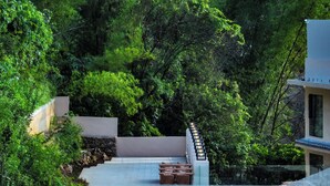 A rooftop terrace with a stone wall, a seating area, and a glass railing overlooking a lush garden. - Yun Pu Yun Shan Se Hotel (Guilin)