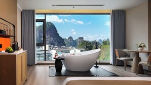 A modern hotel room with a large bathtub, a dining area, and a view of a mountainous landscape. - Yun Pu Yun Shan Se Hotel (Guilin)