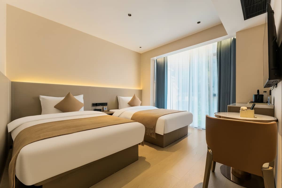 Ein Hotelzimmer mit zwei Betten, einem kleinen Tisch und einem Stuhl.