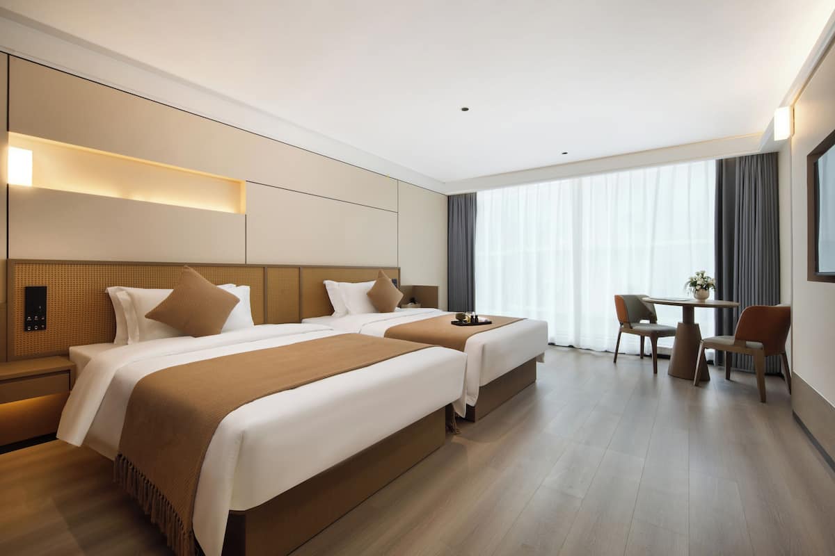 Ein Hotelzimmer mit zwei Betten, einem Schreibtisch und einem Stuhl.