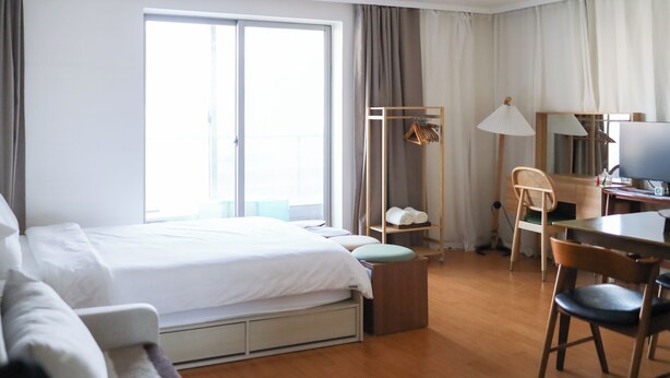 Hotellihuone, jossa on sänky, työpöytä, tuoli, vaatekaappi ja suuri ikkuna.