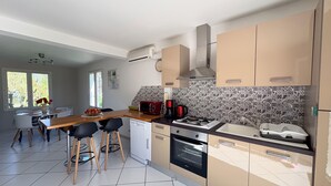 A modern kitchen with a wooden countertop, a built-in oven, and a gas stove. There is a dining area with a table and chairs.