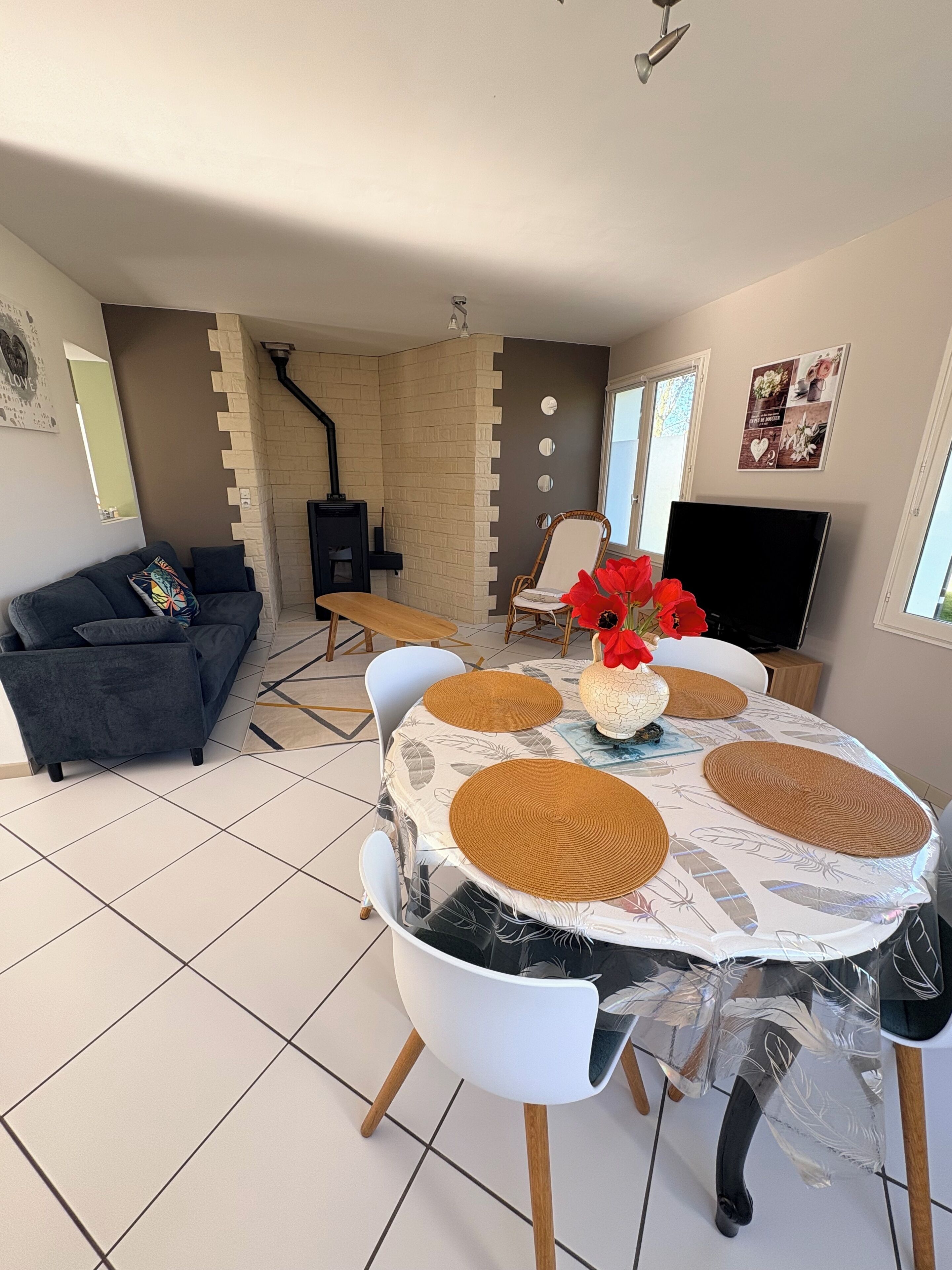 A living room with a sofa, a dining table with placemats, a TV, and a fireplace.