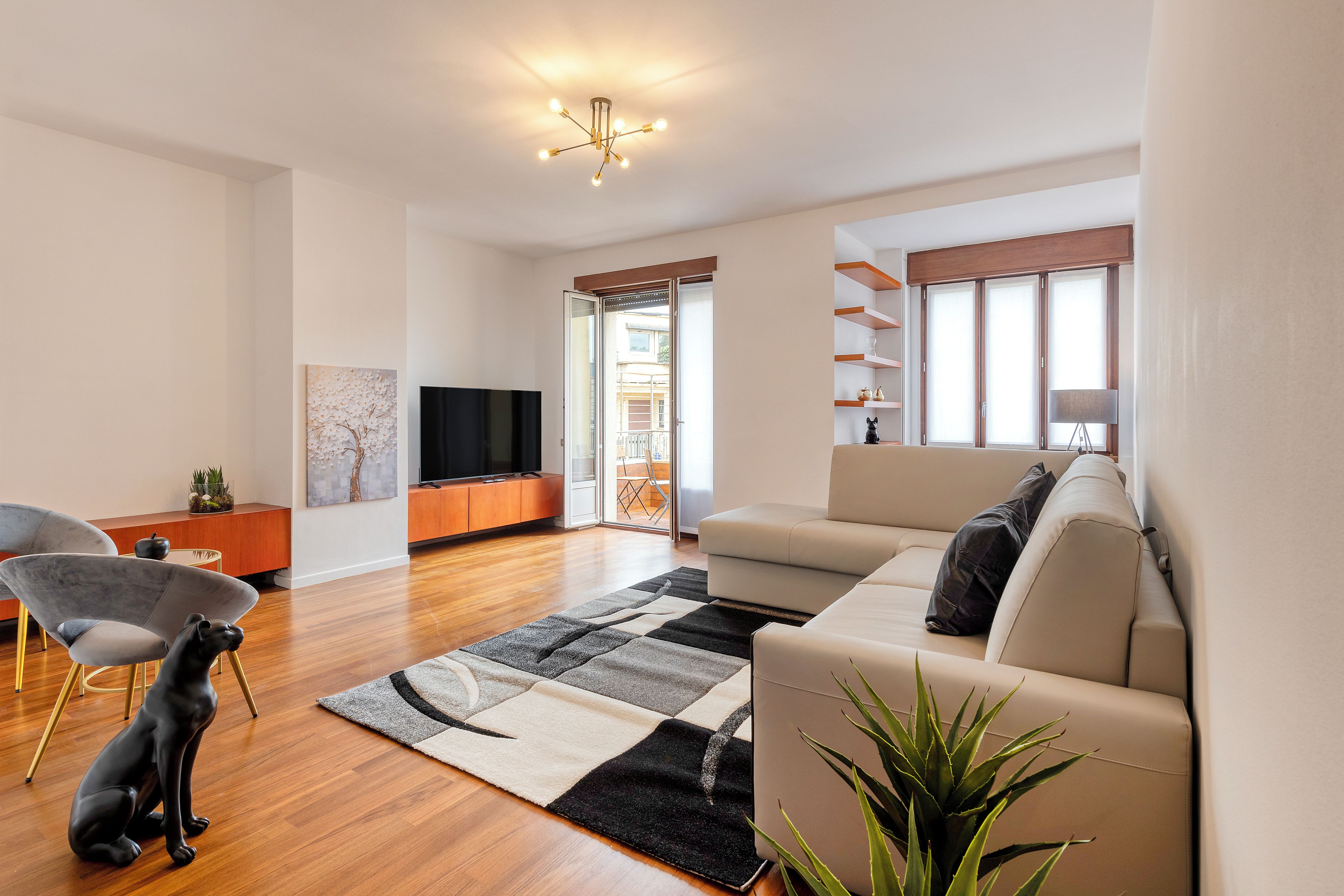A modern living room with a sofa, a television, a coffee table, and a decorative dog statue.