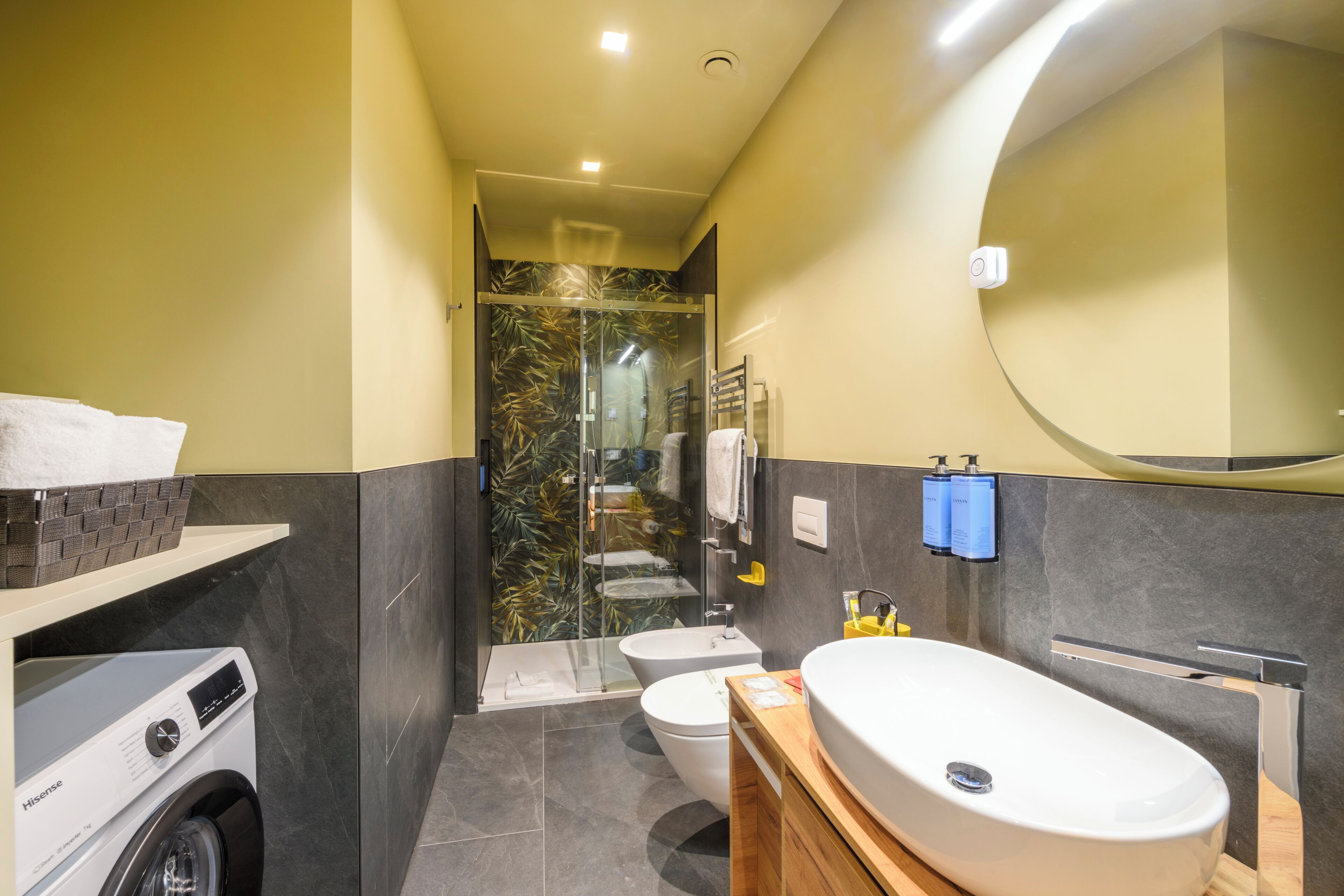 A modern bathroom with a washing machine, toilet, and a large sink.