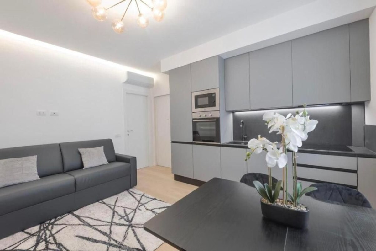 A modern kitchen with grey cabinets, a built-in oven, and a microwave.