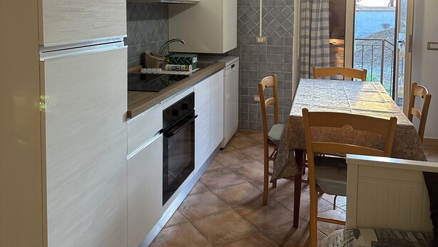 Een keuken met een eethoek, een inbouwoven, een fornuis en een raam met uitzicht.
