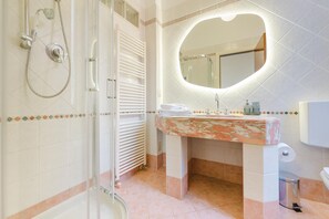 A bathroom with a shower, a sink with a marble countertop, a mirror with a heart-shaped frame, and a toilet. - The Queen of Venice (Venice)