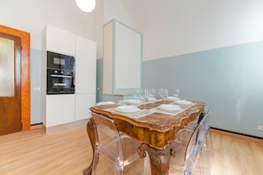 A dining area with a wooden table set for six, a built-in oven, and a white cabinet. - The Queen of Venice (Venice)