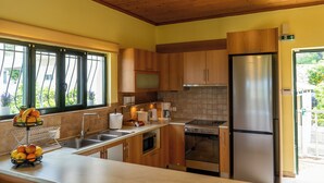 Une cuisine avec des meubles de rangement en bois, des appareils électroménagers en acier inoxydable, un évier et une fenêtre avec des rideaux.