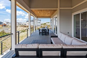 A covered outdoor deck with a dining table and chairs, a sofa, and a view of the surrounding neighborhood. - Gorgeous 5-bedroom house in tranquil Westport with AC (Westport)