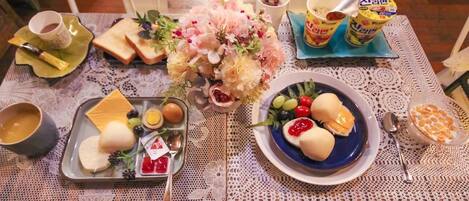 Une table dressée avec une variété d’aliments, notamment du pain, des fruits et des condiments, disposés sur une nappe en dentelle.