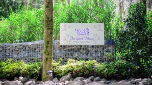 A sign for 'The Guest Village' at Hakone Ashinoko Resort, surrounded by greenery and rocks. - THE GUEST VILLAGE Hakone Ashinoko (Hakone)