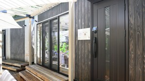 Een modern gebouw met een houten terras, een schuifdeur en een bordje met het nummer B.
