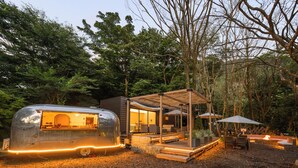 Un camping-car moderne doté d’un coin cuisine, d’une terrasse en bois et de sièges extérieurs.